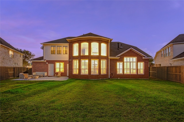 back of property with brick siding, a fenced backyard, a yard, and a patio