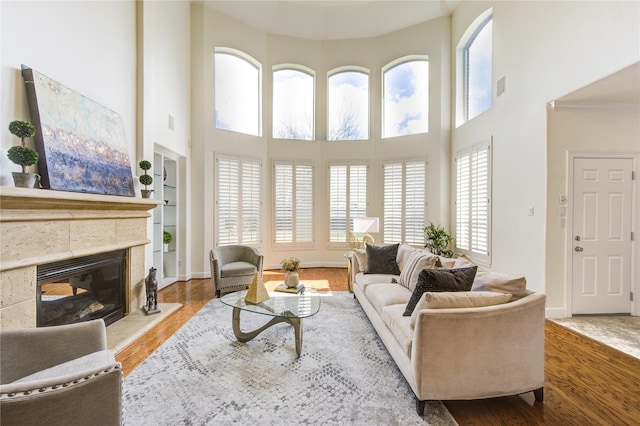 living area featuring baseboards, visible vents, wood finished floors, and a glass covered fireplace