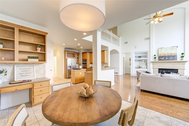 dining space featuring light tile patterned floors, a high ceiling, a fireplace, and visible vents