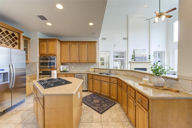 kitchen featuring stainless steel appliances, a peninsula, a sink, visible vents, and a center island