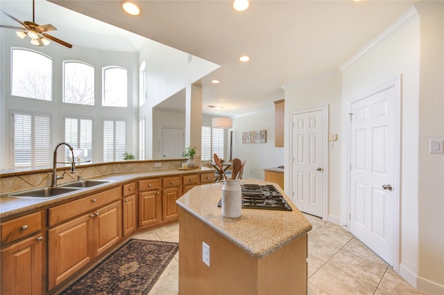 kitchen featuring recessed lighting, brown cabinetry, stovetop with downdraft, light tile patterned flooring, and a sink