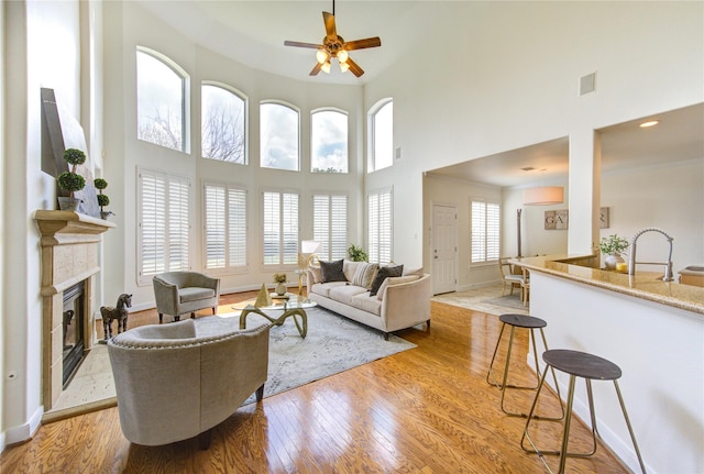 living room featuring light wood-type flooring, baseboards, visible vents, and a glass covered fireplace