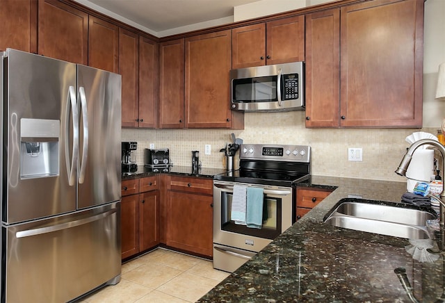 kitchen featuring sink, tasteful backsplash, dark stone countertops, light tile patterned floors, and stainless steel appliances