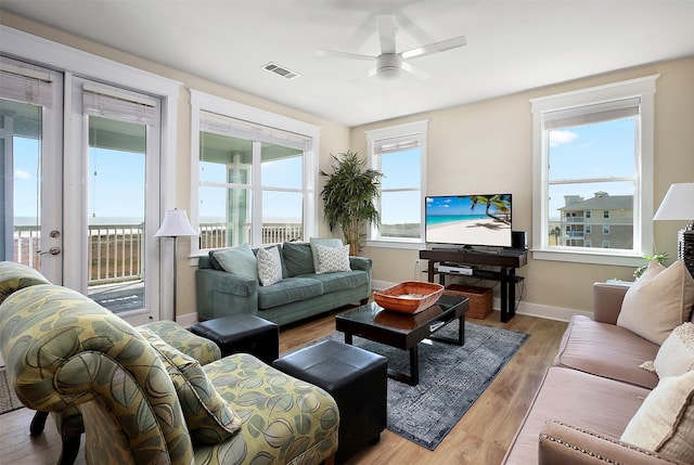 living room with plenty of natural light, ceiling fan, and light wood-type flooring