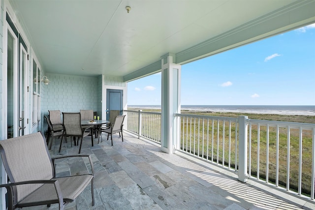 balcony with a water view and a view of the beach