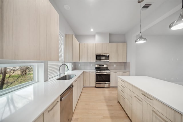 kitchen featuring pendant lighting, sink, stainless steel appliances, tasteful backsplash, and light brown cabinets