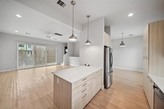 kitchen with light hardwood / wood-style flooring, ceiling fan, appliances with stainless steel finishes, light brown cabinetry, and decorative light fixtures