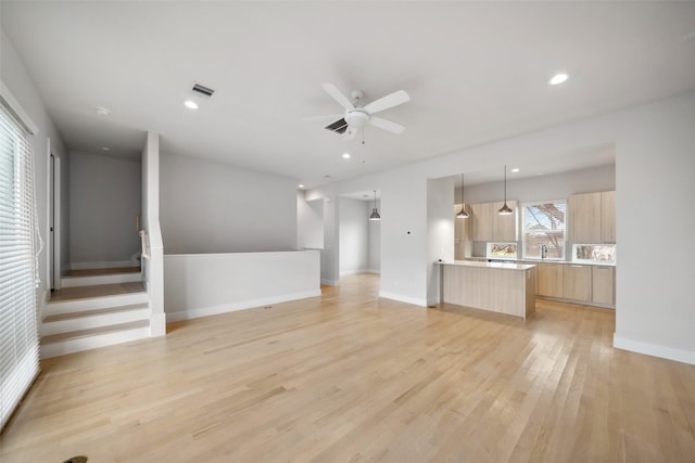 unfurnished living room with ceiling fan, sink, and light hardwood / wood-style floors