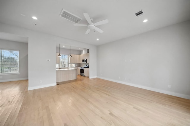 unfurnished living room featuring ceiling fan and light hardwood / wood-style floors