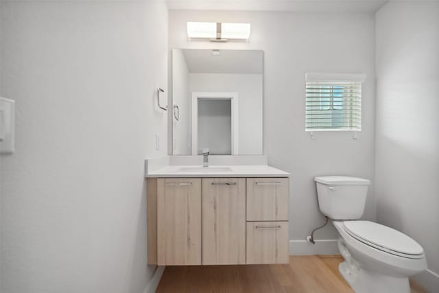 bathroom featuring a skylight, vanity, wood-type flooring, and toilet