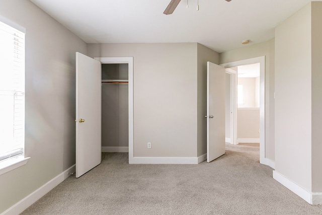 unfurnished bedroom featuring light carpet, a closet, and ceiling fan