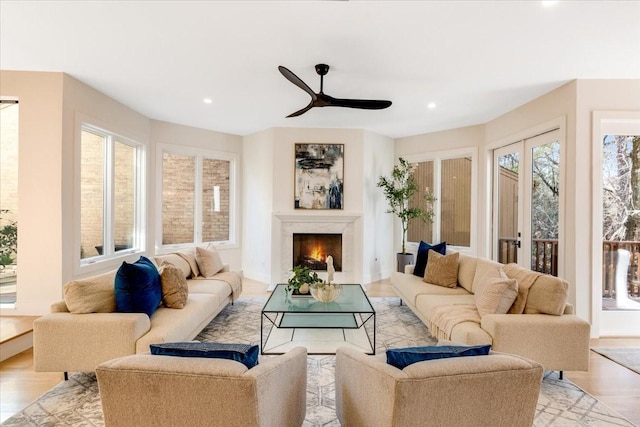 living room with ceiling fan, light wood-type flooring, a high end fireplace, and french doors