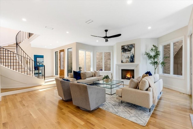 living room with a healthy amount of sunlight, ceiling fan, and light hardwood / wood-style flooring