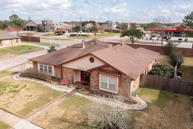 view of front of home featuring a front yard, brick siding, fence, and roof with shingles