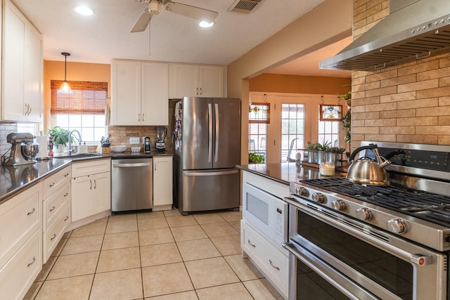 kitchen featuring a sink, visible vents, white cabinets, appliances with stainless steel finishes, and wall chimney range hood