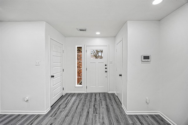 entrance foyer with visible vents, a textured ceiling, baseboards, and wood finished floors