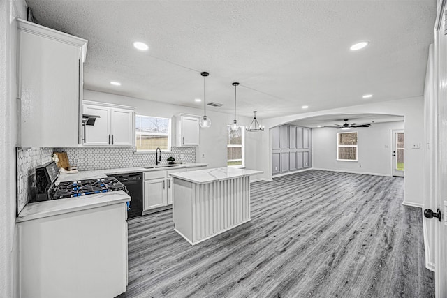 kitchen featuring dishwasher, open floor plan, a center island, stainless steel range oven, and white cabinetry