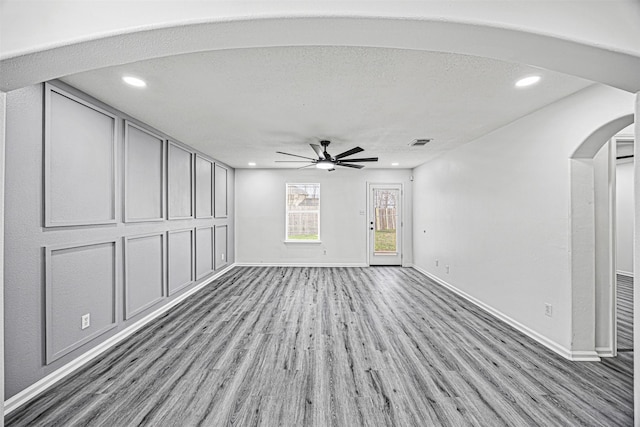 interior space featuring baseboards, arched walkways, a ceiling fan, wood finished floors, and recessed lighting