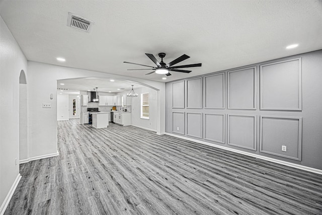 unfurnished living room featuring arched walkways, ceiling fan, recessed lighting, wood finished floors, and visible vents