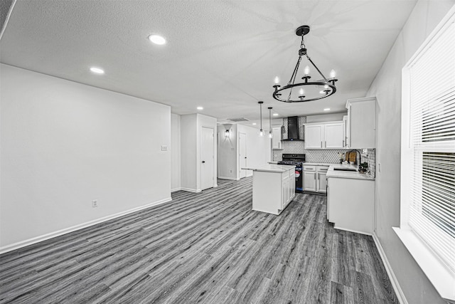 kitchen featuring white cabinets, range, wall chimney exhaust hood, decorative light fixtures, and a center island