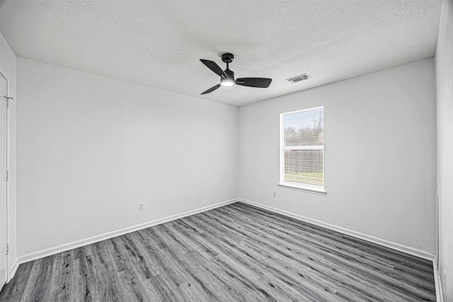 empty room featuring visible vents, dark wood-style flooring, a ceiling fan, and baseboards