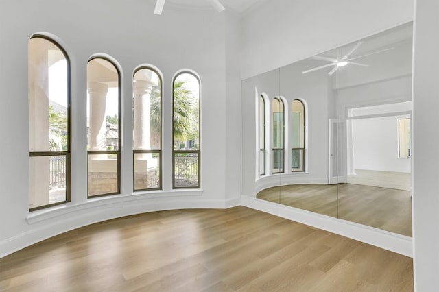 spare room featuring a towering ceiling, ceiling fan, and light hardwood / wood-style floors