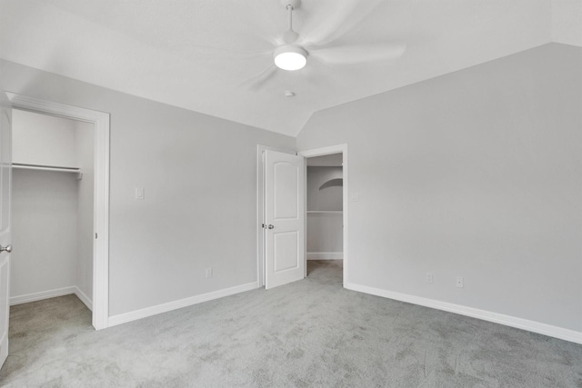 unfurnished bedroom with a spacious closet, vaulted ceiling, and light colored carpet