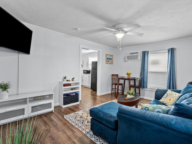 living room with ornamental molding, dark wood-type flooring, a textured ceiling, and a wall unit AC