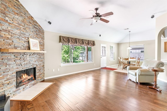 living room with wood finished floors, a fireplace, a ceiling fan, and vaulted ceiling