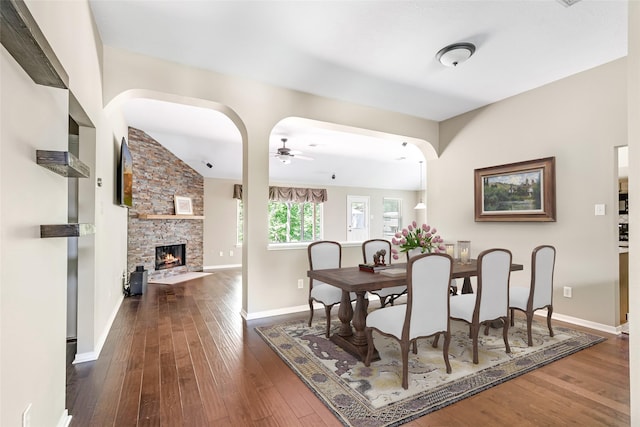 2203 Blossom Creek Dr, Houston, TX 77339 - dining area with ceiling fan, dark wood-style floors, arched walkways, a stone fireplace, and vaulted ceiling