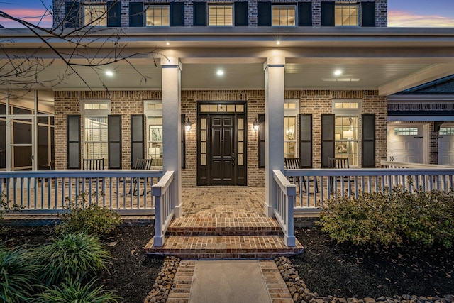 view of exterior entry with covered porch and brick siding