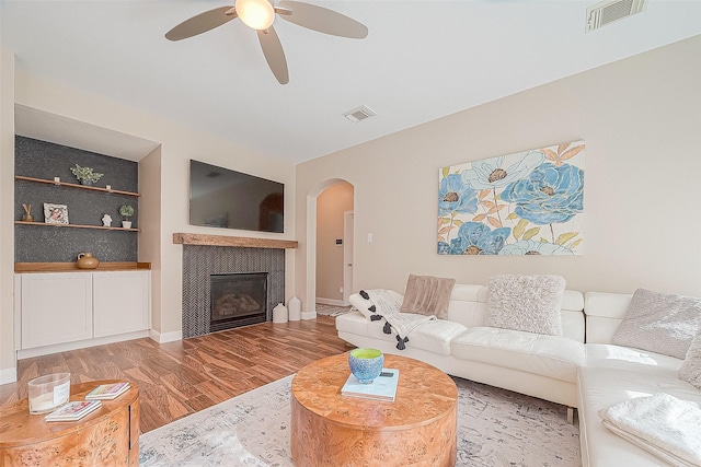 living room featuring hardwood / wood-style floors, ceiling fan, and built in shelves