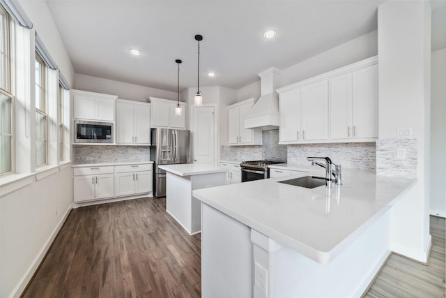 kitchen featuring premium range hood, white cabinetry, decorative light fixtures, kitchen peninsula, and stainless steel appliances