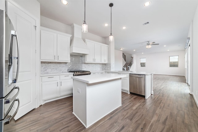 kitchen featuring white cabinetry, a kitchen island, custom range hood, and appliances with stainless steel finishes