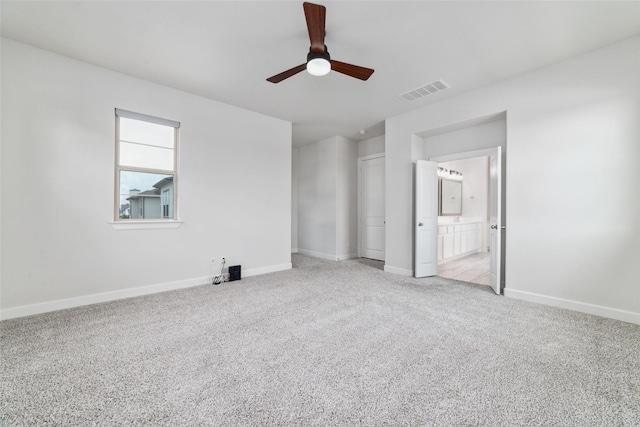 unfurnished bedroom with light colored carpet, ceiling fan, and ensuite bathroom