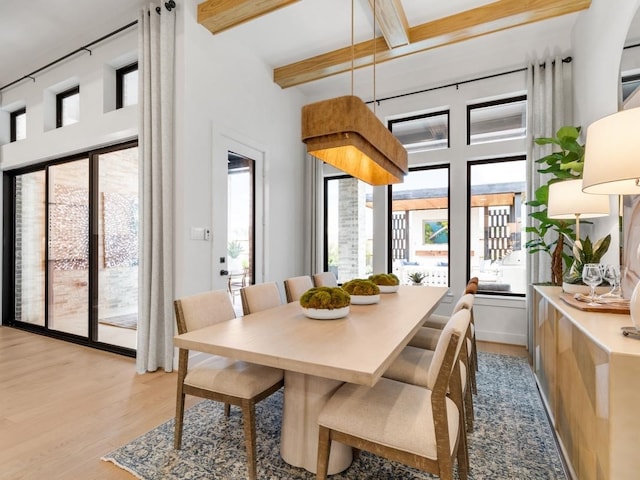 dining room featuring beamed ceiling and light wood-type flooring