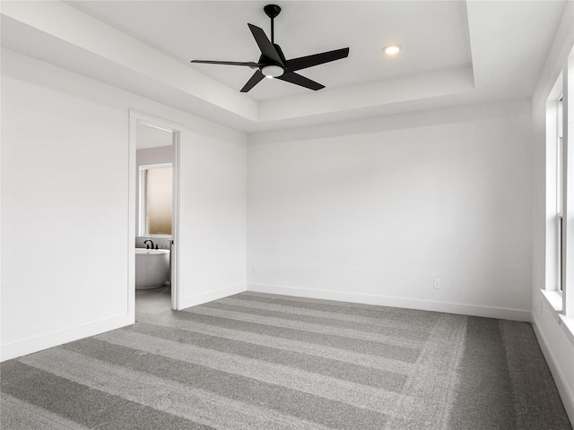 carpeted spare room with ceiling fan and a raised ceiling