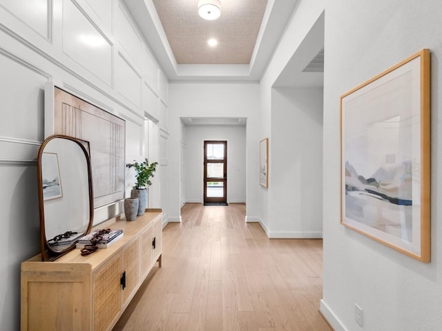 foyer entrance featuring a tray ceiling and light hardwood / wood-style flooring