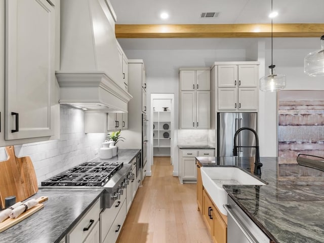 kitchen with premium range hood, appliances with stainless steel finishes, pendant lighting, and white cabinets