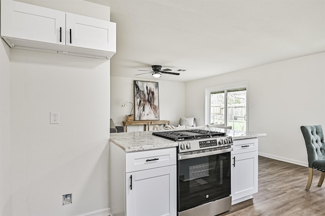 kitchen with white cabinetry, hardwood / wood-style flooring, light stone counters, and stainless steel gas range oven