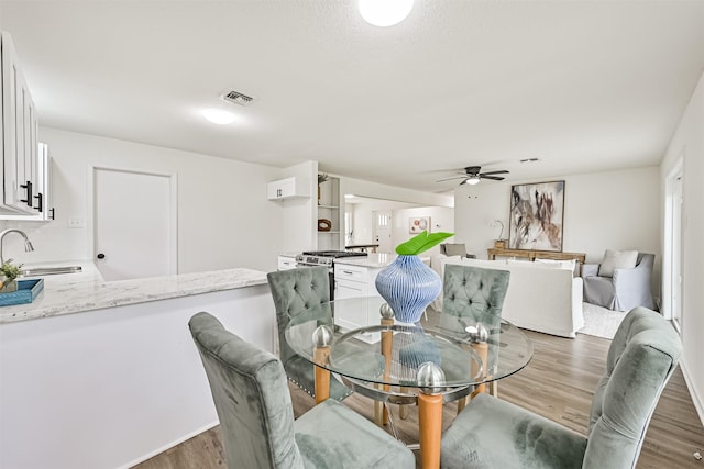 dining area with ceiling fan, dark hardwood / wood-style flooring, and sink