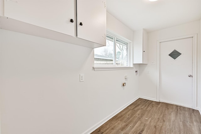 laundry room featuring cabinets, electric dryer hookup, and light hardwood / wood-style floors