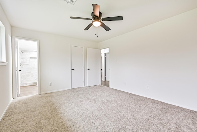 unfurnished bedroom with ceiling fan, ensuite bathroom, and carpet flooring