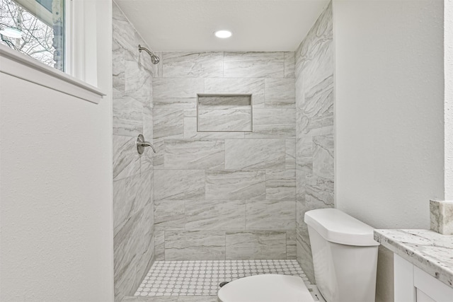 bathroom featuring vanity, tiled shower, and toilet