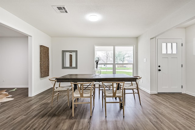 dining space with dark hardwood / wood-style floors and a textured ceiling