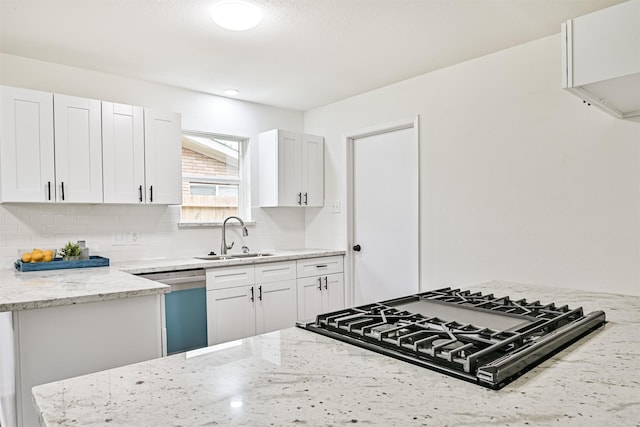 kitchen featuring tasteful backsplash, sink, white cabinets, stainless steel dishwasher, and light stone counters