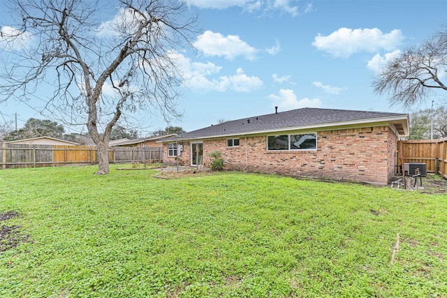 rear view of property featuring central air condition unit and a lawn