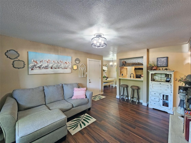 living room with a textured ceiling, dark hardwood / wood-style floors, and a chandelier