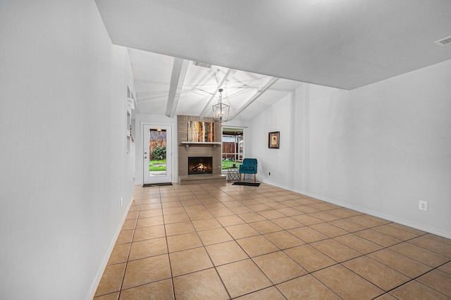 unfurnished living room featuring an inviting chandelier, a brick fireplace, light tile patterned floors, and vaulted ceiling with beams