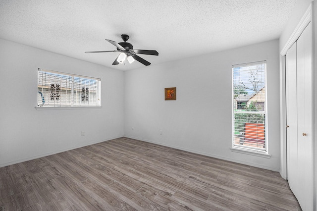 empty room featuring a textured ceiling, ceiling fan, and light wood-type flooring